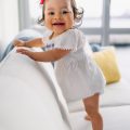 smiling toddler girl standing on sofa
